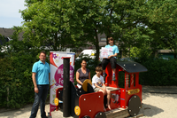 Ein Mann und eine Frau mit zwei Kindern an einer Spielplatz-Lokomotive.