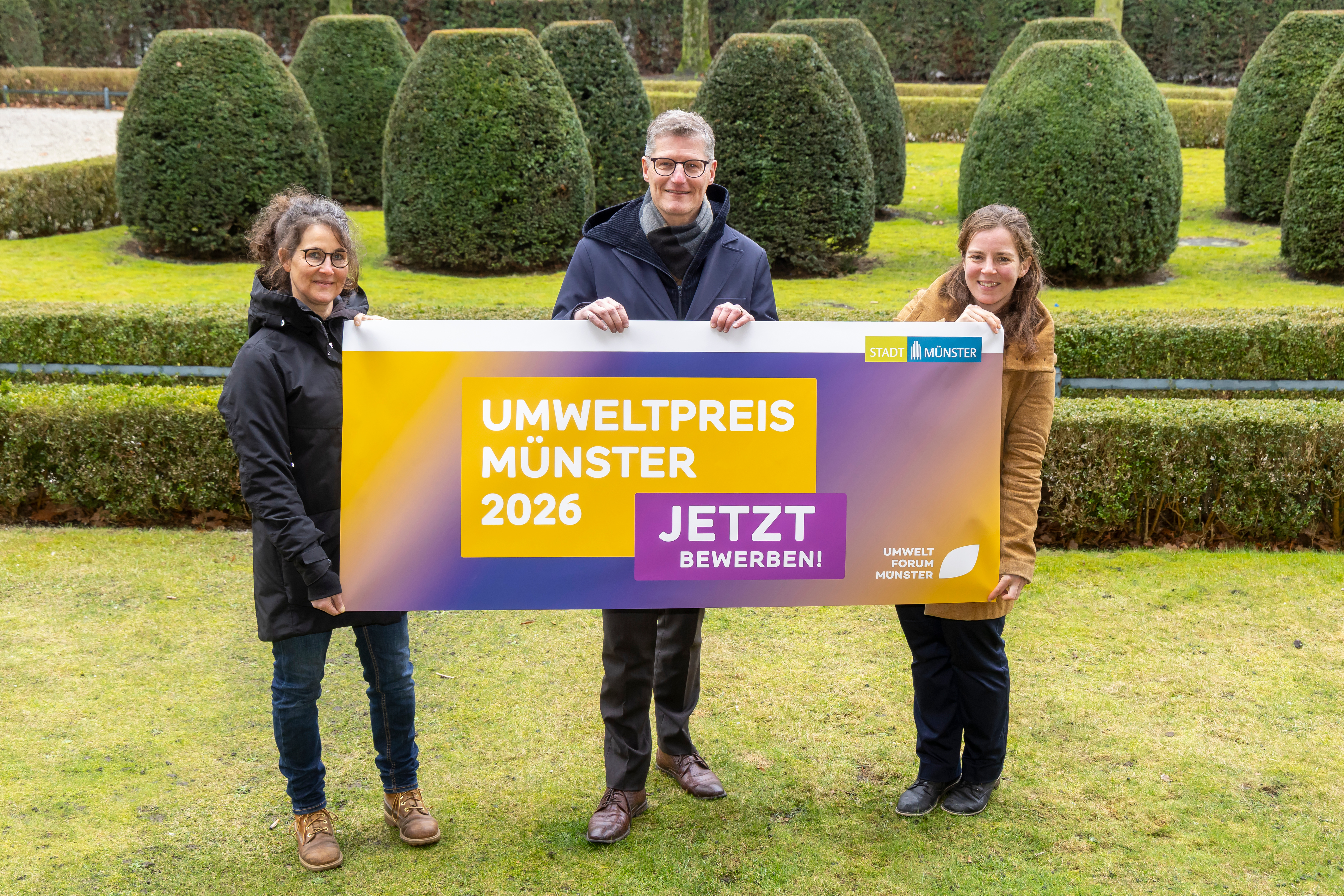 Anke Feige, Projektleiterin Umweltforum, Oberbürgermeister Tilman Fuchs, Giulia Paltrinieri für das Amt für Gründflächen zeigen das Banner für den Umweltpreis der Stadt Münster.