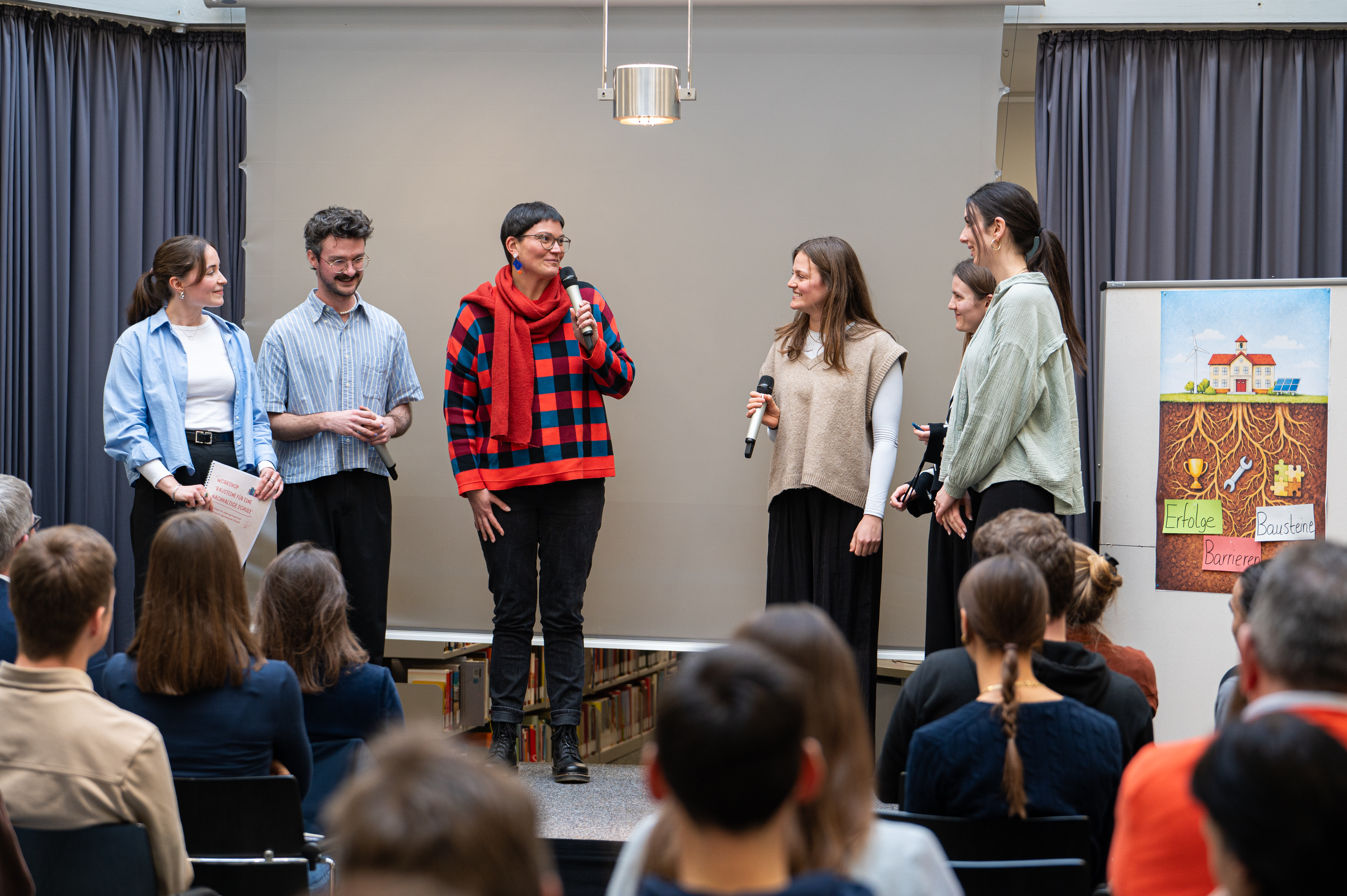 Personen aus dem BNE-Netzwerk in Münster im Gespräch auf einer Bühne.