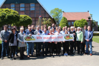 Ressourcen sparen und effizienter nutzen - das Ziel des ÖKOPROFIT-Projektes Die beteiligten Unternehmen der ÖKOPROFIT mit einem Banner, der die Aufschrift trägt: 'Wir machen mit!'