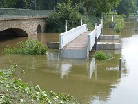 Hochstehender Fluss, der unter einer Brücke herfließt und dessen starke Strömung extreme Kräfte entwickeln kann