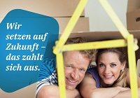 Titel: "Wir setzen auf Zukunft - das zahlt sich aus - Klimafreundlich bauen. Förderung nutzen." Zu sehen: Ein Paar, das durch ein zum Haus gefalteten Zollstock in die Kamera schaut.