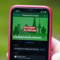Auf einem roten Smartphone ist die Kleine Tat Sharing-App geöffnet.