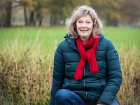 Portraitfoto von KlimaTrainerin Brigitte Gehring, die auf einer Wiese sitzt.