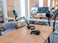 Ein Schreibtisch mit Mikrofonständer und Mikrofon. Setting: Radiostudio.