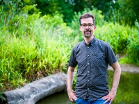 KlimaTrainer Gerald Müller vor einer grünen Fluss-Landschaft