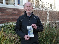 Mann hält Flyer vom Repair Café im SKA Treff in die Kamera.