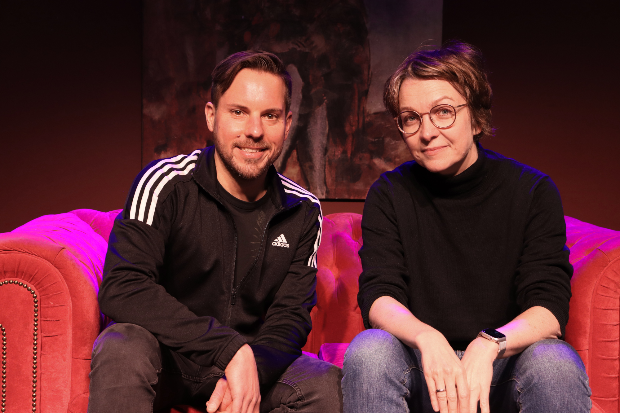 Autor Olivier Garofalo und Regisseurin Tanja Weidner sitzen auf einem roten Sofa. 
