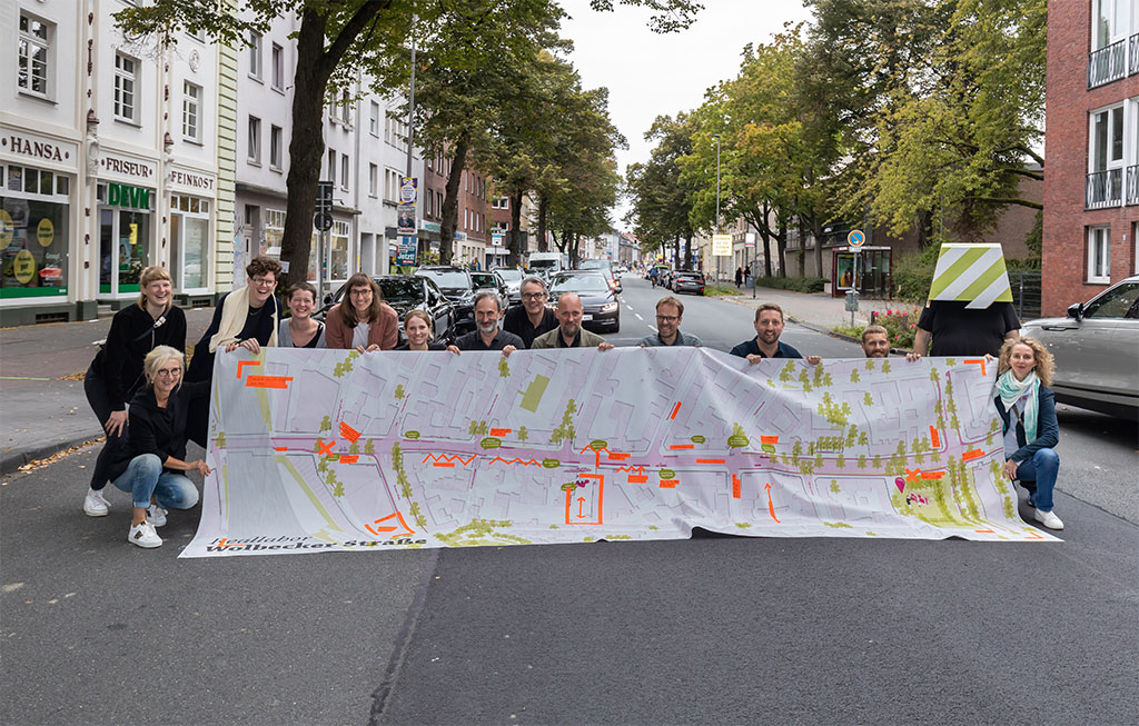 Vertreterinnen und Vertreter der Büros Urban Catalyst (Berlin), modulorbeat (Münster) und SHP Ingenieure (Hannover), Stadtbaurat Robin Denstorff sowie Mitarbeitende von Münster Marketing und des Amtes für Mobilität und Tiefbau kamen am Samstag zum Hansaplatz und stellten erste Ergebnisse des Reallabors Wolbecker Straße vor. 