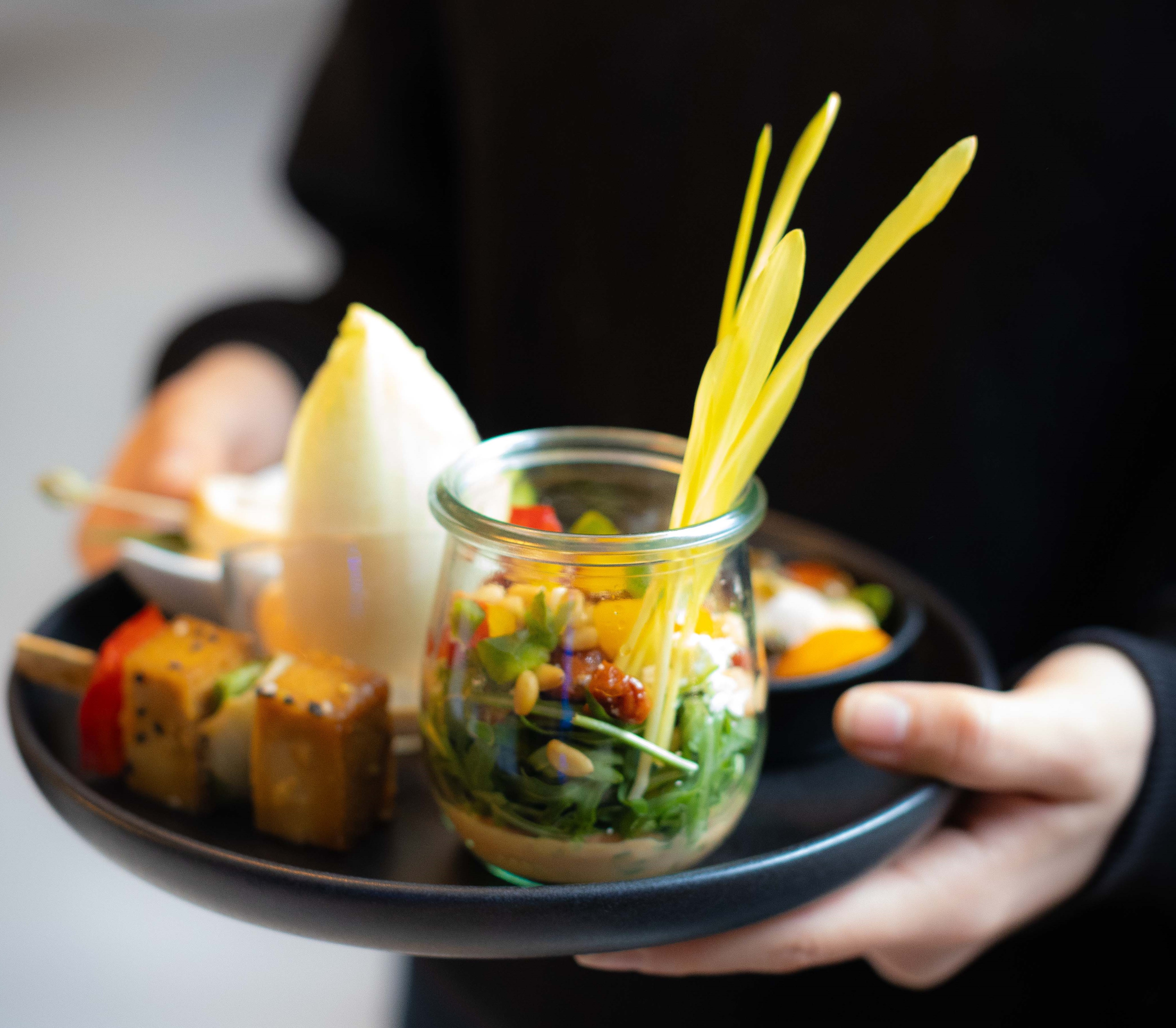 Ein ansprechendes Gericht auf einem schwarzen Teller vom Cateringservice Mundus in Nahaufnahme.