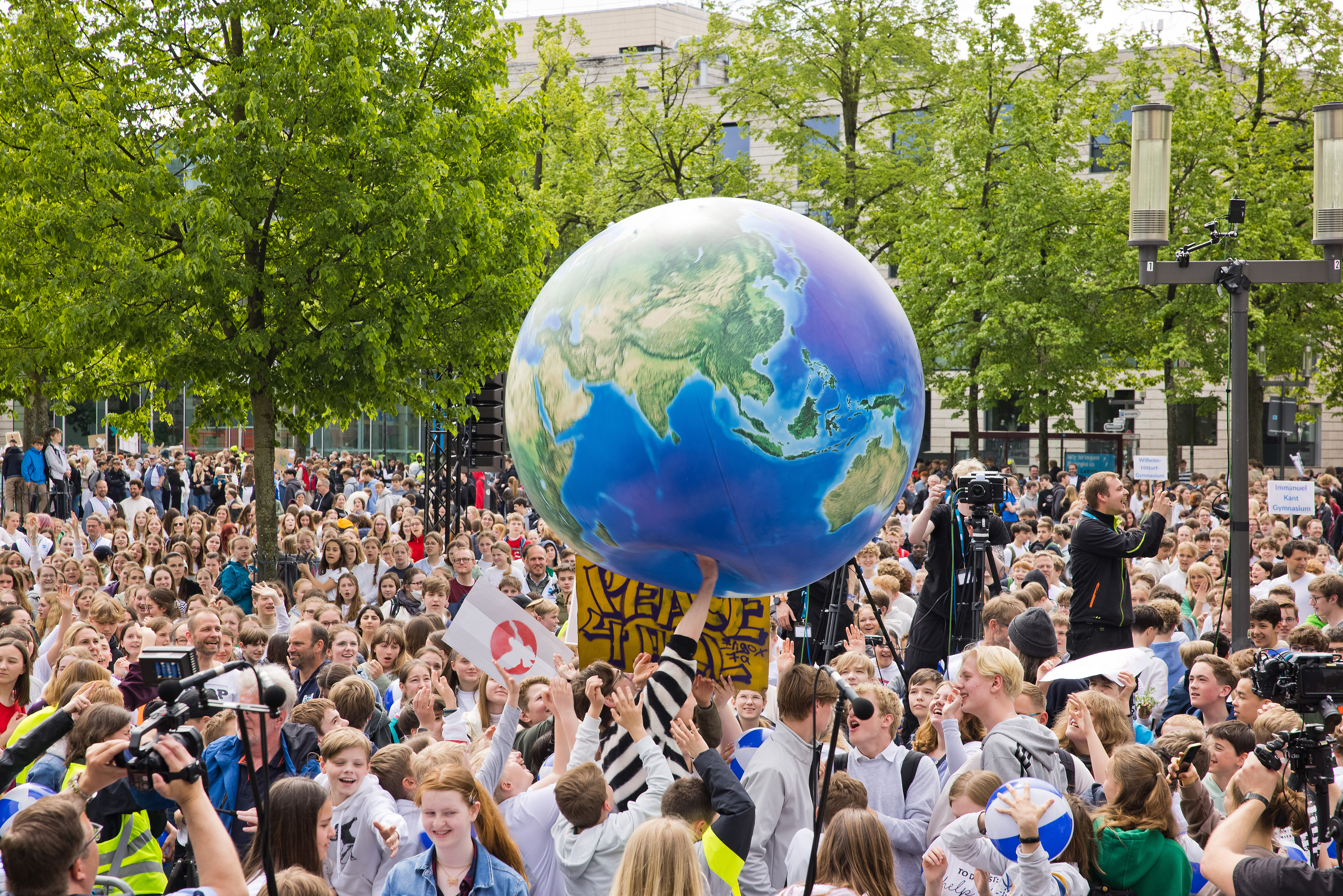 Zur Eröffnung des Friedensjubiläums 2023 wird ein symbolischer Erdball über die Köpfe einer Menschenmenge weitergereicht. 