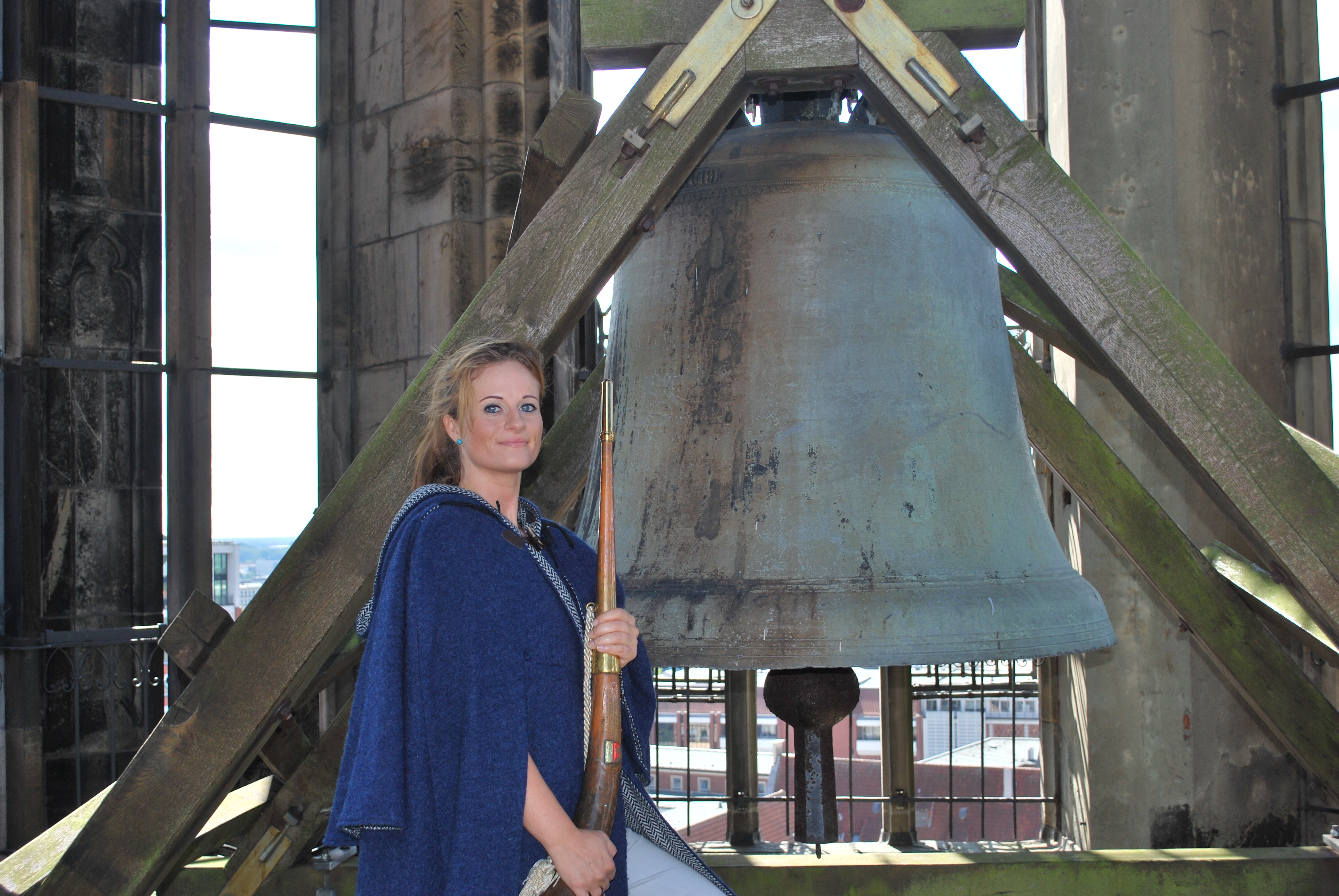 Die Türmerin vor einer Glocke.