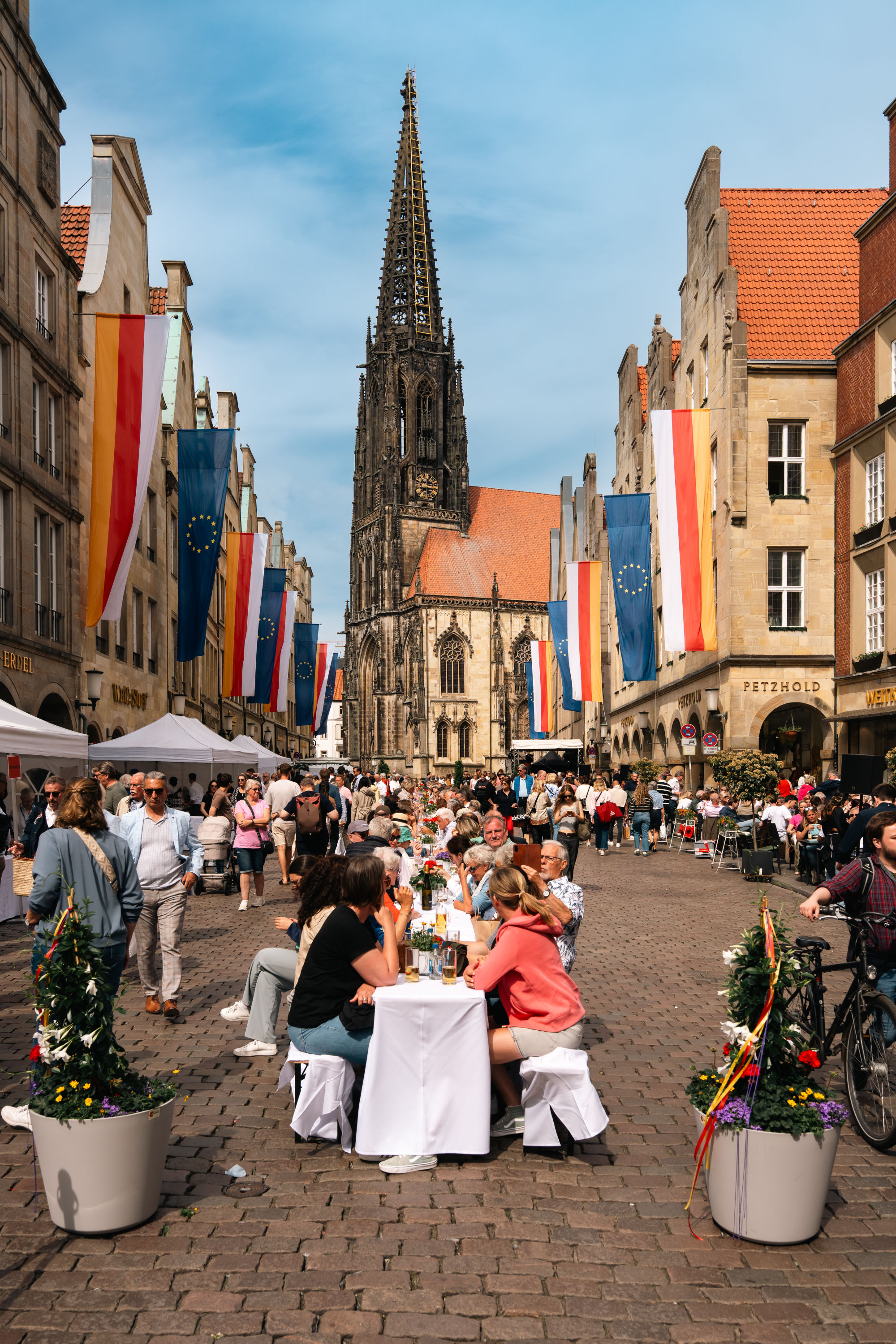 Personen genießen an einer langen weißen Tafel auf dem Prinzipalmarkt das Hansemahl.