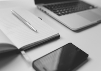 Laptop, Block und Handy auf einem Schreibtisch Foto