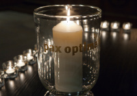 Kerze in einem Glas mit der Aufschrift 'Pax optima rerum' (Der Frieden ist das beste aller Dinge)