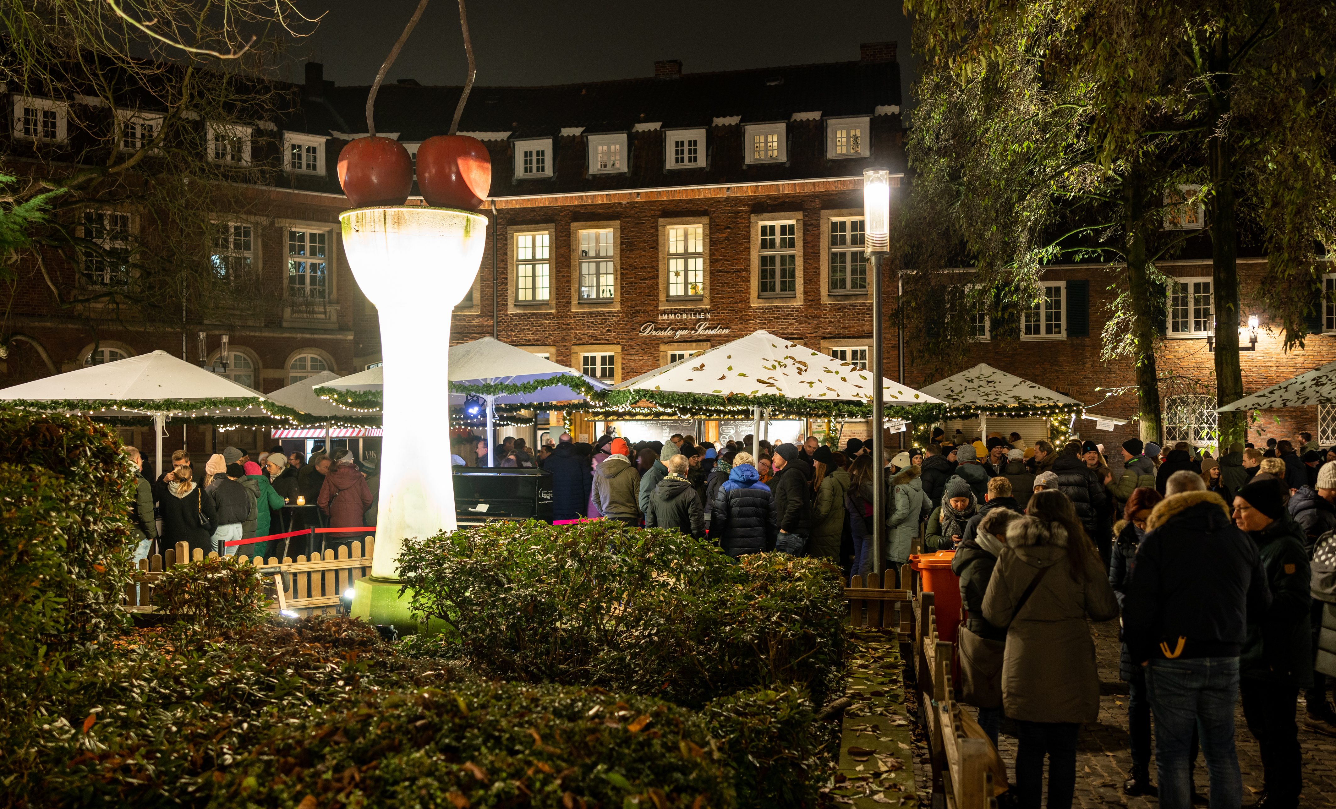 Abendliche Stimmung auf dem Weihnachtsmarkt mit Kirschen-Skulptur am Harsewinkelplatz