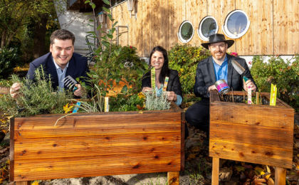 3 Menschen hinter einem Hochbeet sitzend