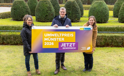 Drei Personen halten ein Poster mit dem Schriftzug Umweltpreis 2026 hoch