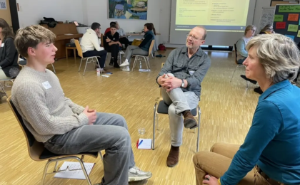 Drei Menschen sitzen sich gegenüber und unterhalten sich.