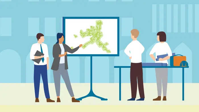 Das Symbolbild zeigt zwei Personen, die etwas an einem Bildschirm erklären 