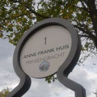 Auf dem Foto ist ein Schild zu sehen, auf dem in niederländisch der Ort, nämlich das Anne Frank Haus, angezeigt wird.