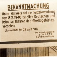 Auf einem großen Warnschild steht 'Bekanntmachung: Unter Hinweis auf die Polizeiverordnung vom 8.2.1940 ist allen Deutschen und Polen das Betreten des Ghettogebietes verboten. Litzmannstadt, den 22. April 1940. Der Polizeipräsident Schäfer SS-Brigadeführer'