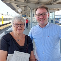 Stefan Querl steht neben Uta Leichsenring auf einem Bahnsteig. Beide lächeln in die Kamera.