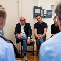 In einem Ausstellungsraum der Villa ten Hompel sitzen mehrere Polizistinnen und Polizisten mit Mitarbeitenden zusammen und sprechen miteinander.