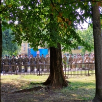 Offizielle Gedenkfeier an den Ghetto-Aufstand unter Beteiligung der polnischen Armee und US-Außenminister Blinken. (Foto: Villa ten Hompel/Peter Römer) Auf einem Platz mit Bäumen stehen Soldaten, im Hintergrund ist eine Leinwand mit der Videoüber-tragung des US-Außenministers Blinken, der vor einem blauen Hintergrund neben einer amerikani-schen Flagge spricht.