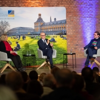 Drei Menschen sitzen auf einem Podium