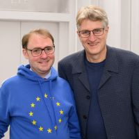 Zwei Männer stehen nebeneinander und lächeln in die Kamera