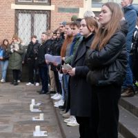 In einem Innenhof stehen mehrere Schüler*innen. Vor ihnen stehen mehrere Kerzen.