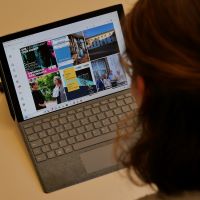 Eine Person sitzt vor einem Tablet und blickt auf Bilder auf Instagram.