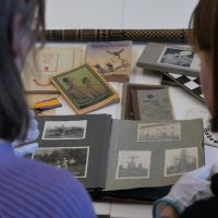 Zwei Personen sitzen an einem Tisch und blicken auf historische Dokumente.