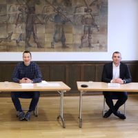 Teilnehmende und Moderation des Gesprächs sitzend an Tischen.