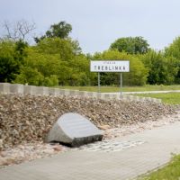 Denkmal in Form eines Bahnsteigs mit Gedenkstein neben einem Bahnhofschild mit der Aufschrift 'Staca Treblinka'.