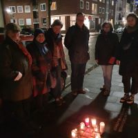 Gruppe von Menschen im Dunkeln vor den Stolpersteinen der Familie Gumprich und Kerzen