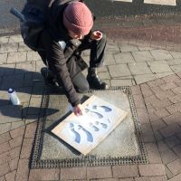 Rahel Thiel sprüht Kreide über eine Fußstapfen-Schablone