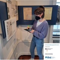 Karolin Baumann schreibt Notizen vor einer Ausstellungswand zur Verfolgung von Sinti.