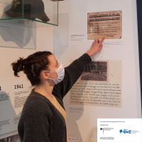 Kim Sommerr zeigt in der Ausstellung auf die Plakette eines Schutzbunkers