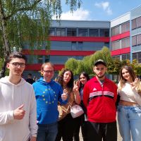 Stefan Querl und Jugendliche stehen nebeneinander auf dem Schulhof