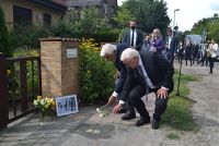 Steinmeier und Adorf legen Blume am Stolperstein nieder, im Hintergrund Zuschauende