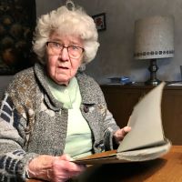 Margot Janning sitzt mit einer Akte in der Hand an einem Tisch
