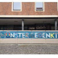 Banner mit der Aufschrift "Münster gedenkt" auf blauem Hintergrund vor dem Gebäude des Stadthauses