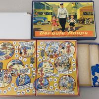 Spieldeckel des Brettspiels mit der Abbildung eines Polizisten, der Kinder über die Straße führt, daneben das Spielfeld und Spielsteine.