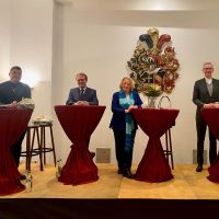 vier Diskussionsteilnehmende hinter Stehtischen auf dem Podium
