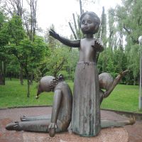 Statue eines Mädchens, links neben ihr eines Clowns mit gesenktem Kopf