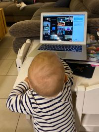 Baby vor einem Laptop, auf dem die Online-Lesung zu sehen ist