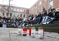 Schülerinnen und Schüler sitzen bei einer Gedenkveranstaltung im Rathausinnenhof, im Vordergrund Kerzen