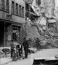 Altes Schwarz-Weiß-Foto zeigt Personen vor einem zerstörten Gebäude